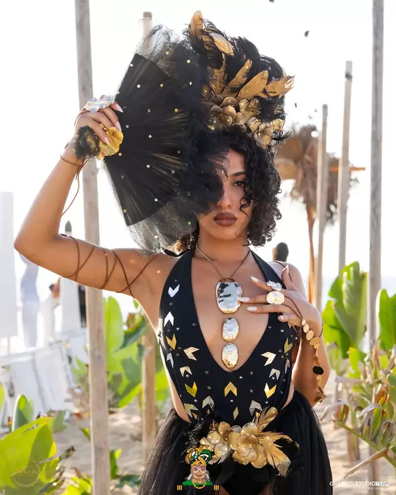 Performer con grande copricapo di piume nere e decori dorati