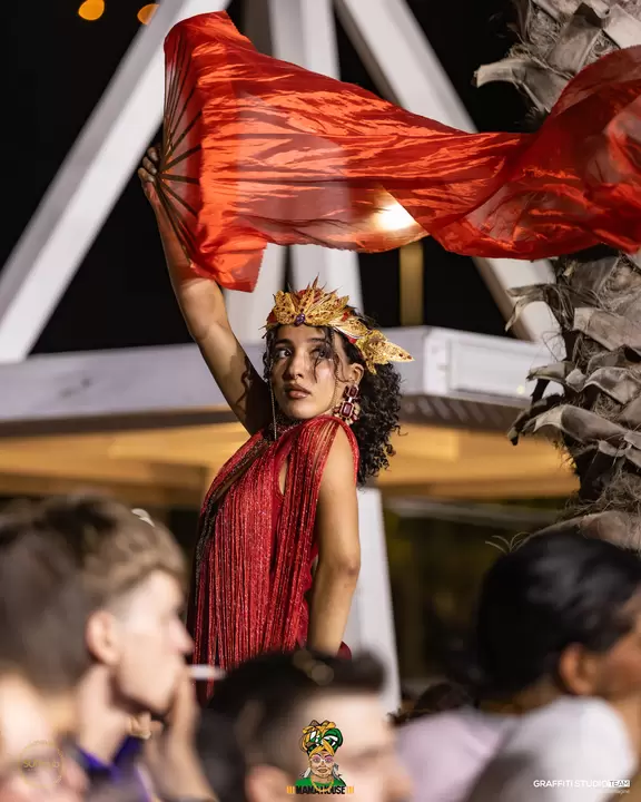 Performer con veli rossi in movimento sopra la folla
