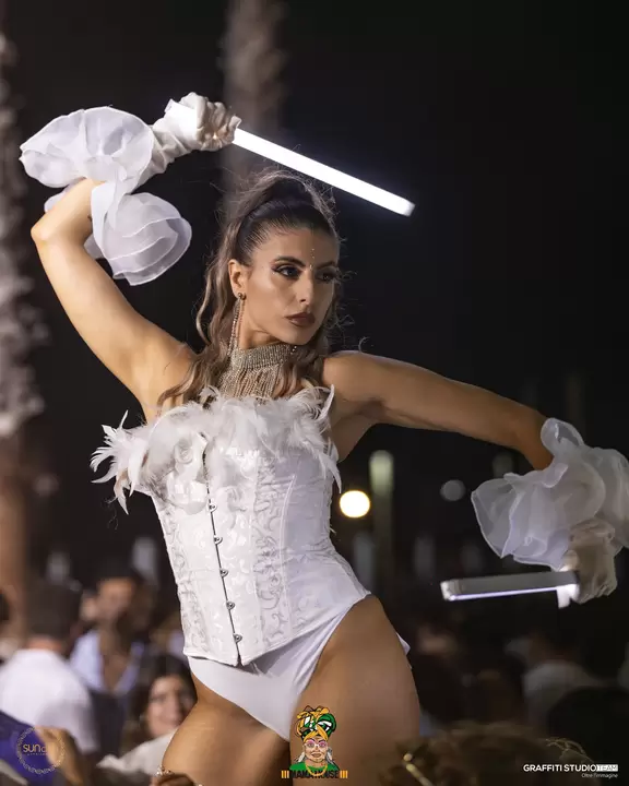 Performer in corsetto bianco con bastoni luminosi