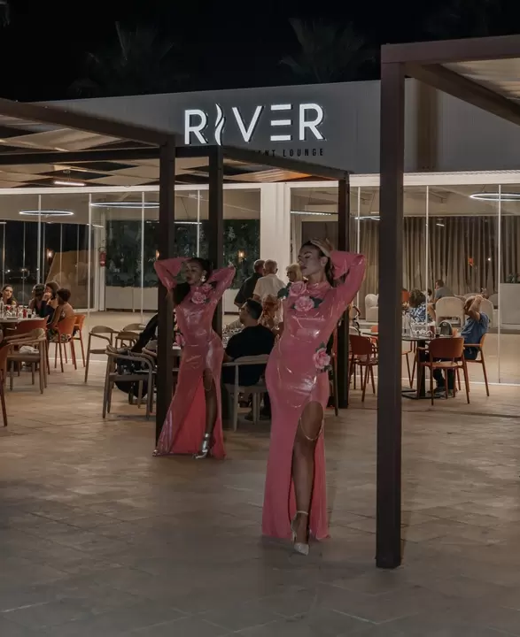 Due performer in abito rosa davanti a un event lounge