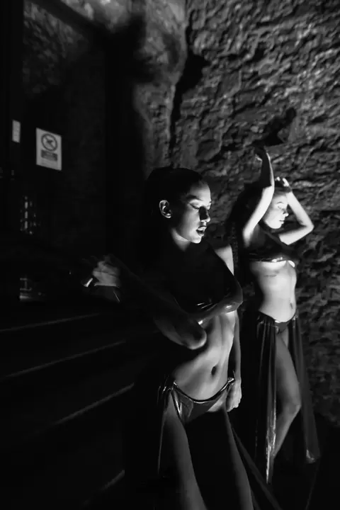 Due performer davanti a una parete di pietra, in bianco e nero