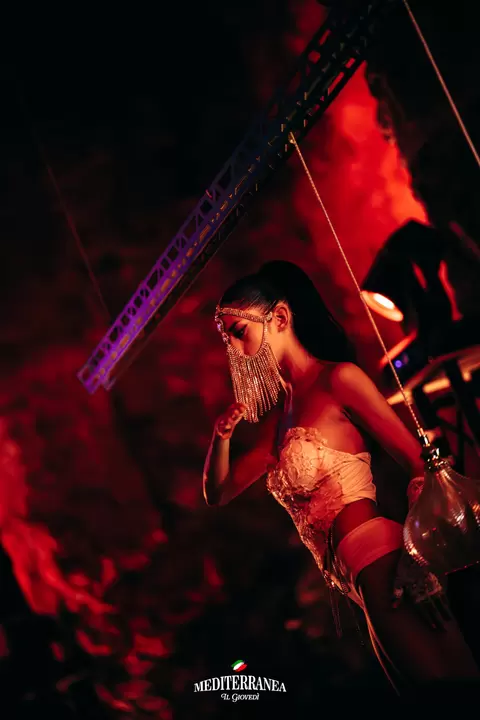 Performer con maschera di cristalli a frange in luce rossa