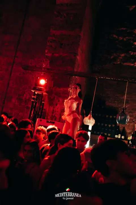 Performer con maschera di cristalli sopra la folla, in luce rossa