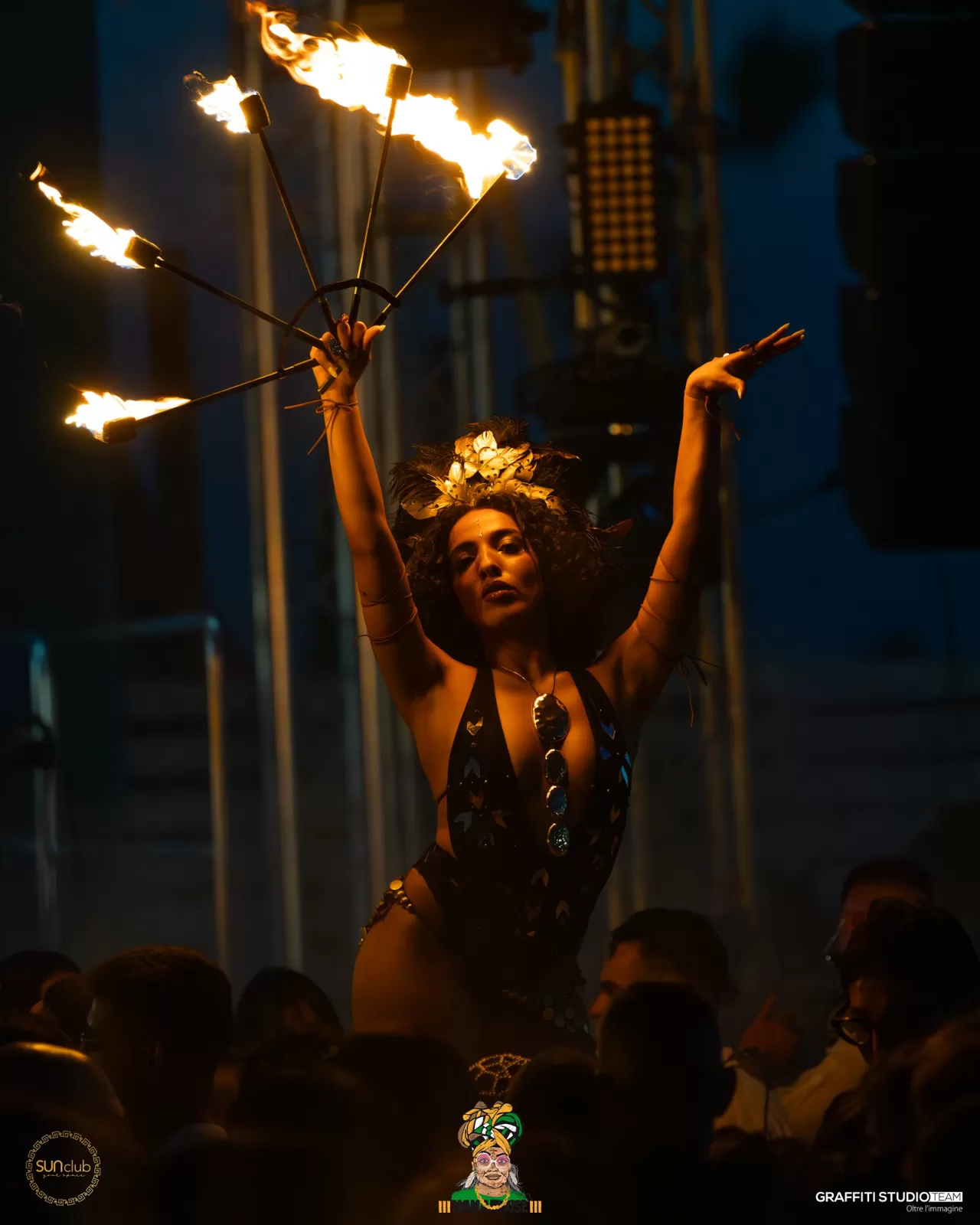 Performer con copricapo dorato e ventaglio di fuoco sopra il pubblico