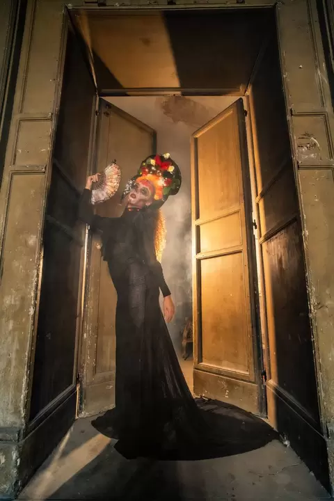 Performer in abito nero di pizzo sulla soglia di una porta antica