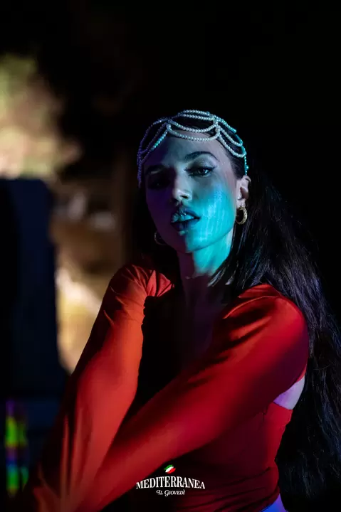 Performer con diadema di perle e abito rosso in luci di scena blu