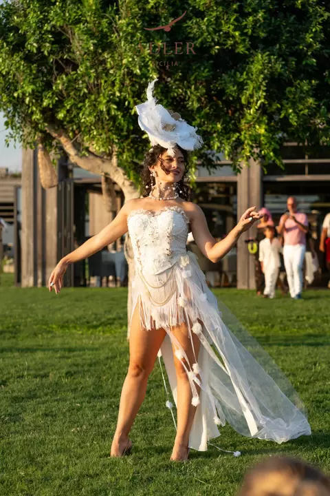 Performer danza sul prato con lo strascico di tulle al vento