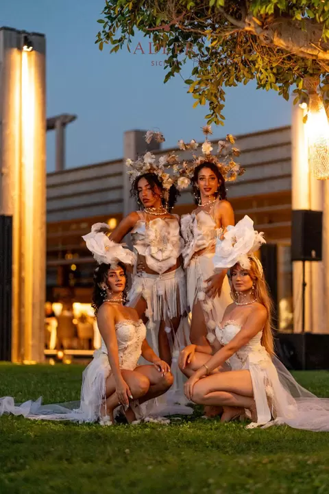 Le quattro performer in posa sotto gli alberi, a sera