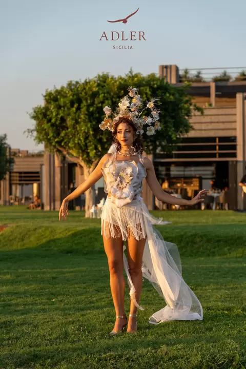 Performer con corona di fiori dorati e strascico di tulle sul prato